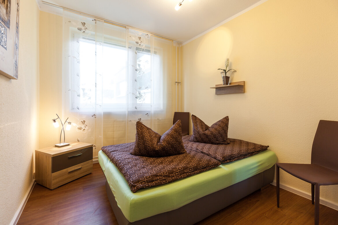 Zweites Schlafzimmer der Gästewohnung mit Doppelbett und Nachtschrank