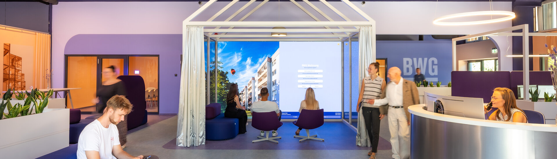 Blick in das Wohnforum mit mehreren Menschen und der LED-Wand des Wohnungskonfigurators im Zentrum