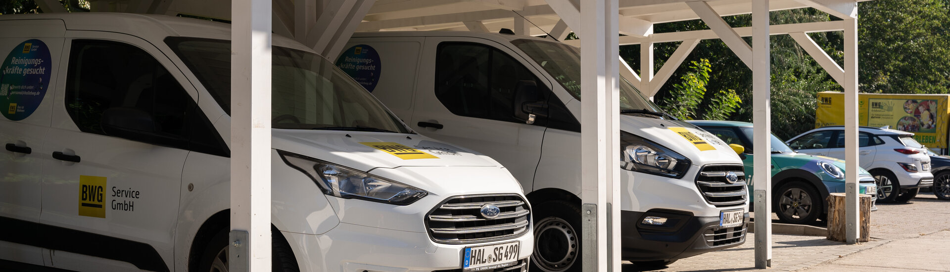 weiße Transporter der BWG Service GmbH unter weißem Carport