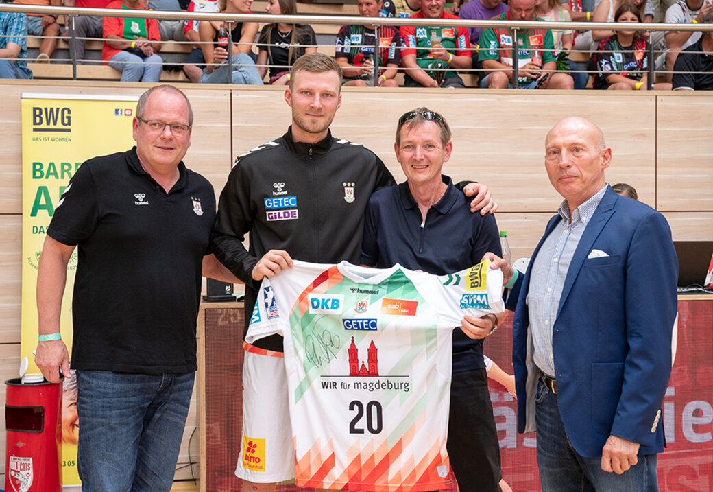 Vorstand Lutz Haake und Ekkehard Weiß halten mit SCM-Spieler Weber ein Trikot