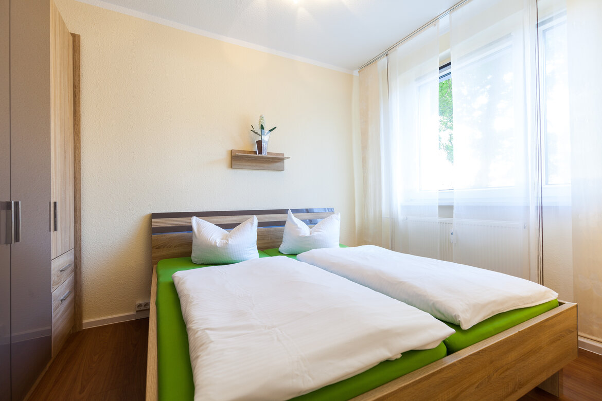 Schlafzimmer der Gästewohnung mit Doppelbett und Schrank