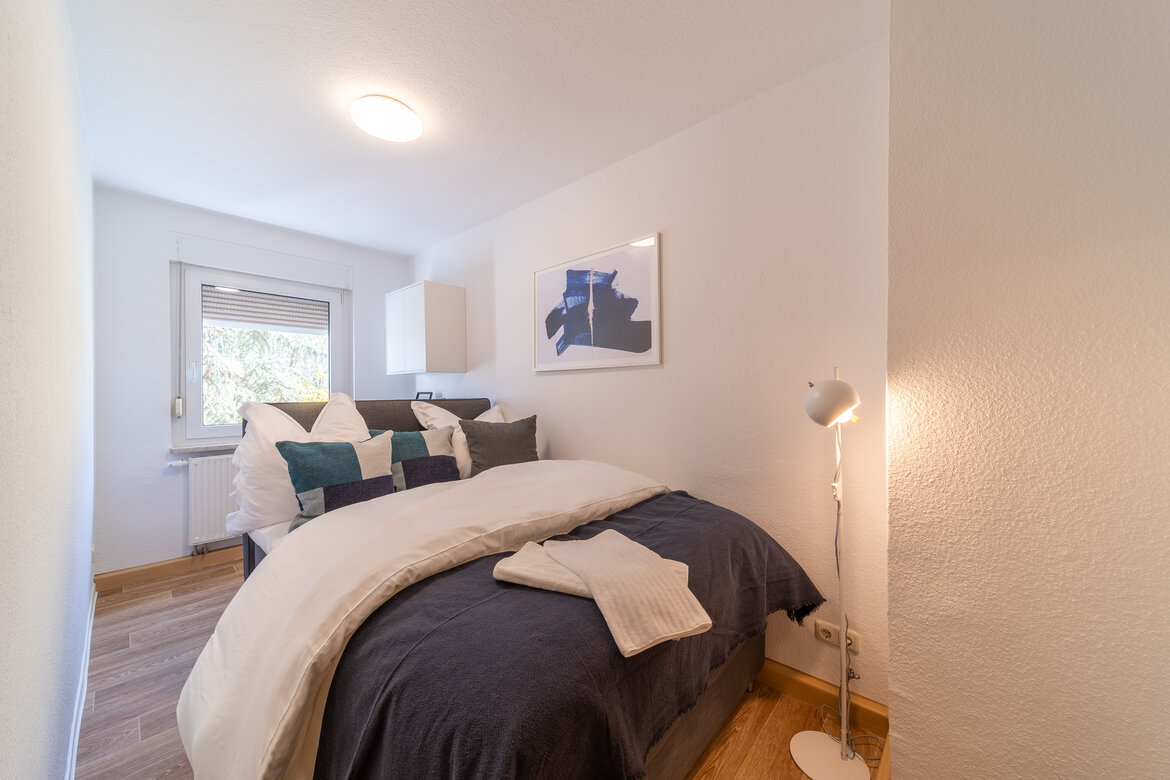 Zweites, kleineres Schlafzimmer mit Doppelbett und Stehlampe