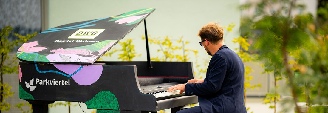 Klavierspieler an einem im BWG-Stil bemalten Klavier