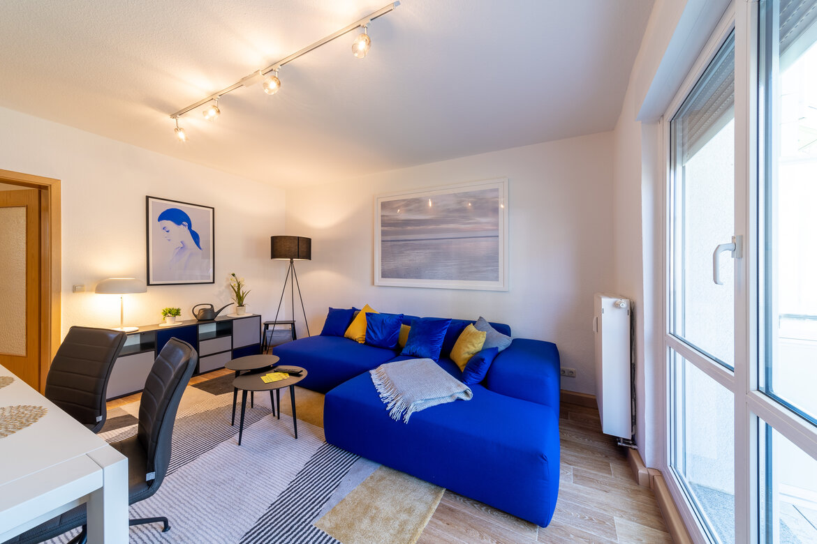 blaue Sofaecke mit Stehlampe, Couchtisch, Kommode und Essbereich