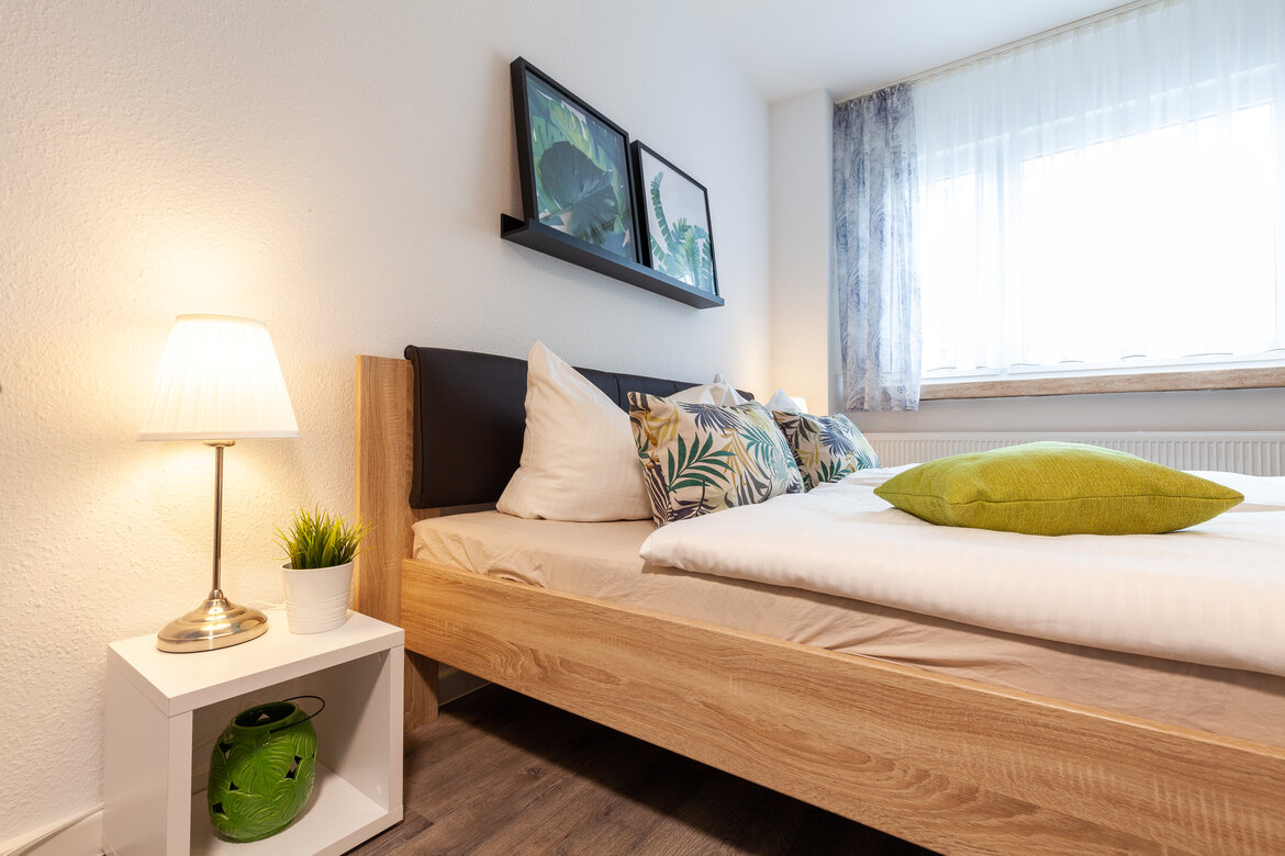Schlafzimmer mit Doppelbett und Nachtschrank mit eingeschalteter Nachttischlampe