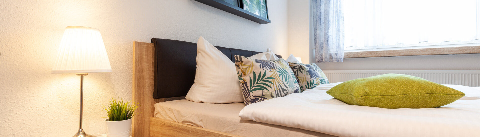Bett in einer Gästewohnung mit eingeschalteter Nachttischlampe