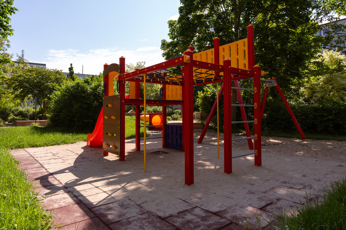 Spielplatz mit roter Rutsche und Kletterstangen